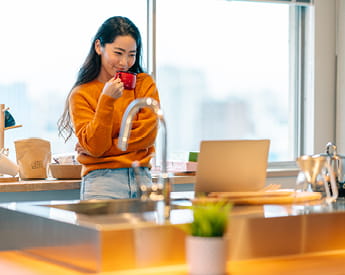 Studying with us | Think Education | Woman drinks coffee while using laptop