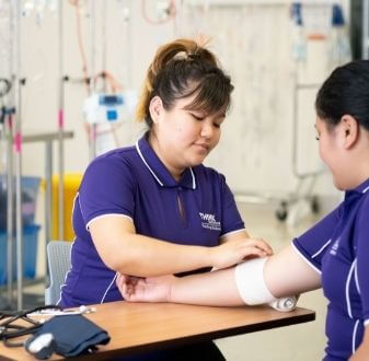 Nursing student applying bandage to other student in clinic